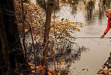 Zwei Enkel und die Großeltern stehen auf einem Steg am See und angeln, umgeben von herbtlicher Landschaft