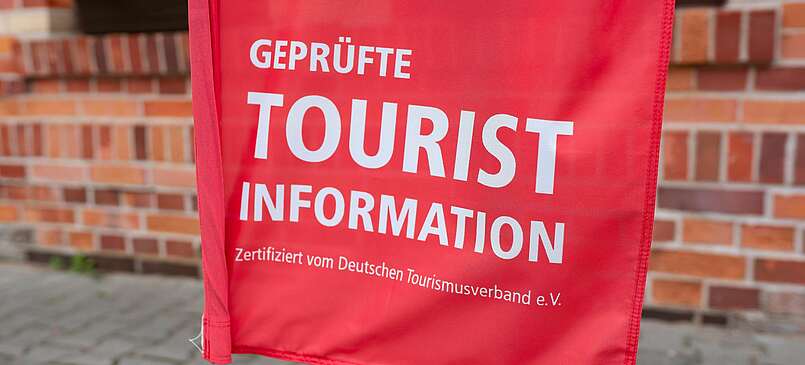 <p>Teilansicht rote Fahne mit Schrift "Touristinfo"</p>