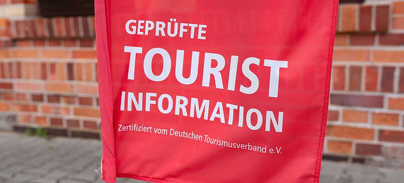 Teilansicht rote Fahne mit Schrift "Touristinfo"