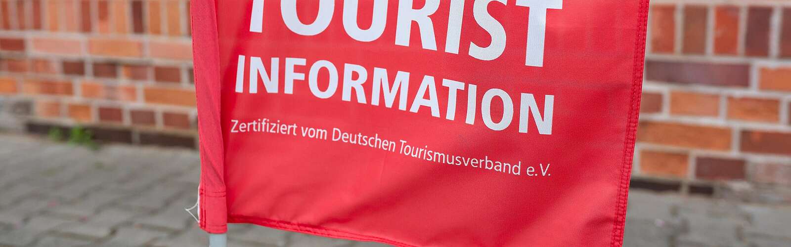 <p>Teilansicht rote Fahne mit Schrift "Touristinfo"</p>